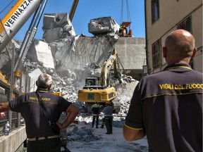 Rescuers inspect the rubble and wreckages at the Morandi motorway bridge, two days after a section collapsed in Genoa on August 16, 2018. - A vast span of the Morandi bridge caved in during a heavy rainstorm in the northern port city on August 14, 2018, sending about 35 cars and several trucks plunging 45 metres (150 feet) onto railway tracks below and killing at least 39 people.
