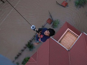 Indian People are airlifted by Navy personnel during a rescue operation at a flooded area in Paravoor near Kochi, in the Indian state of Kerala on August 18, 2018. - Rescuers in helicopters and boats fought through renewed torrential rain on August 18 to reach stranded villages in India's Kerala state as the toll from the worst monsoon floods in a century rose above 320 dead.
