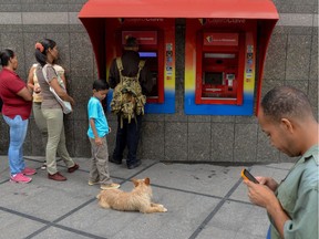 People queue to withdraw money from an ATM in Caracas on August 21, 2018. - Caracas is issuing new banknotes after lopping five zeroes off the crippled bolivar, casting a pall of uncertainty over businesses and consumers across the country.