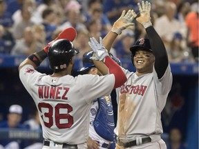 Boston Red Sox' Rafael Devers high fives with teammate Eduardo Nunez after Devers hit a two run home run in the sixth inning of their American League MLB baseball game against the Toronto Blue Jays, in Toronto on Wednesday, August 8, 2018.