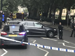 Police cordon off the area on Millbank, in central London, after a car crashed into security barriers outside the Houses of Parliament, in London, Tuesday, Aug. 14, 2018.