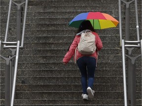 A woman walks up some steps in the rain.