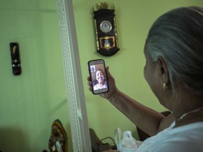 In this Jan. 6, 2017 photo Yolanda Mollinedo looks at her granddaughter Alejandra in Virginia, United States, on her smartphone using a video chat application with the new experimental internet in the living room of her home in Havana, Cuba. The home internet test program selected some 2,000 residents of Old Havana to receive free connections for two months before a planned expansion and the start of billing for the service.