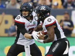 Redblacks quarterback Trevor Harris (7) hands off to William Powell (29) during the first half of Friday's game against the Blue Bombers in Winnipeg.