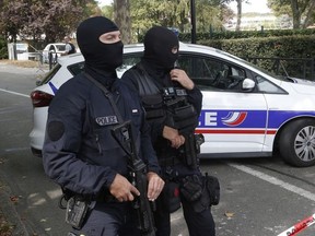 French hooded police officers cordon off the area after a knife attack Thursday, Aug. 23, 2018 in Trappes, west of Paris. A man flagged by French authorities as a suspected radical killed his mother and sister and seriously injured another woman in a knife attack Thursday that was quickly claimed by the Islamic State group.