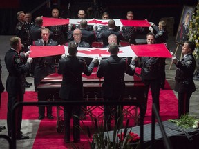 Pallbearers remove the Canadian flags from the caskets at the regimental funeral for constables Robb Costello, and Sara Burns, who were killed in the line of duty, in Fredericton on Saturday, Aug. 18, 2018. The two city police officers were among four people who died in a shooting in a residential area on the city's north side.