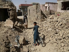 Afghan residents walk near destroyed houses after a Taliban attack in Ghazni on August 16, 2018. - Afghan forces appeared to have finally pushed Taliban fighters from the strategic city of Ghazni on August 15, as shopkeepers and residents warily returned to the streets after days of intense ground fighting and US airstrikes.
