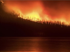 In this photo taken Sunday, Aug. 12, 2018, a fire burns next to Lake McDonald in Glacier National Park in northwest Montana. The fire, which was started by lightning on Saturday night, has forced the evacuation of the Lake McDonald Lodge and a nearby campground.