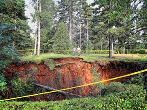 Men look at a sinkhole in Oxford, N.S. on Aug.23, 2018 in a handout photo. A Nova Scotia town is urging the public to take caution as officials scramble to assess the massive, expanding sinkhole that has sucked up surrounding trees and picnic tables.