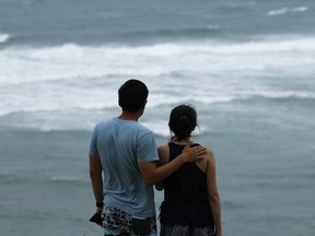 Dan Wong, left, and Cassie Tarleton watch waves crash along the coastline ahead of Lane, Friday, Aug. 24, 2018, in Honolulu. As Lane approaches Oahu, large ocean swells have impacted local beaches and coastlines.