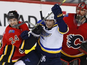 Calgary Flames' Travis Hamonic, left, moves St. Louis Blues' Scottie Upshall from blocking Flames goalie Mike Smith.