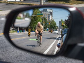 Cyclists ride along Holland Ave near the Queensway overpass.