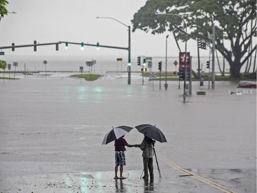 People stand near flood waters from Hurricane Lane making the intersection of Kamehameha Avenue and Pauahi Street in Hilo impassable on Thursday. Hollyn Johnson/Hawaii Tribune-Herald