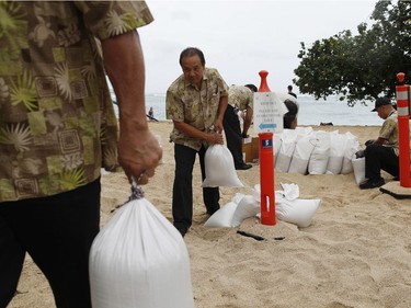 Employees of the Sheraton Waikiki fill sandbags along the beach in preparation for Hurricane Lane in Honolulu on Thursday.