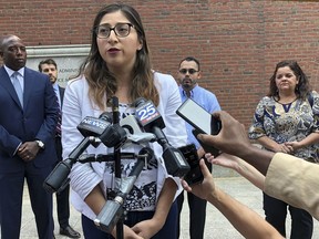 Lilian Calderon answers questions during a lunch break outside federal court, Monday, Aug. 20, 2018, in Boston, as her husband, Luis Gordillo, center back, and others stand nearby. The American Civil Liberties Union argued a case on behalf of them and four other couples that federal immigration officials are violating the rights of immigrants seeking legal status by setting a deportation "trap" at their required marriage interviews.
