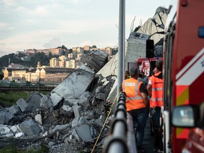 Emergency personnel search through debris from the collapsed Morandi motorway bridge in Genoa, Italy, on Tuesday, Aug. 14, 2018.