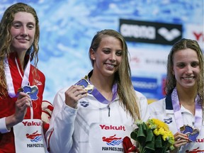 Kathleen Baker of the U.S., center, poses with her medal on the podium after winning the women's 200m backstroke final with second-placed Taylor Ruck of Canada, left, and third-placed Regan Smith of the U.S., during the Pan Pacific swimming championships in Tokyo, Sunday, Aug.12, 2018.