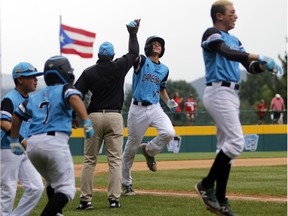 Puerto Rico's Carlos De Jesus high-fives his coach as he rounds the bases after hitting a home run against Canada on Wednesday.