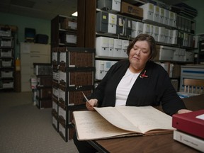 Nancy Hurn, an archivist at the Anglican Church of Canada in Toronto, pores over an old Keewatin register marking baptisms, burials, marriages and confirmations, as part of her work in attempting to help families who have lost relatives somewhere in the residential school system, Thursday, August 23, 2018.