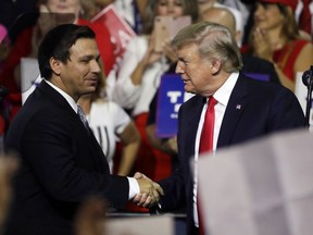 FILE - In this July 31, 2018, file photo, President Donald Trump, right, shakes hands with Florida Republican gubernatorial candidate Ron DeSantis during a rally in Tampa, Fla. Florida voters are going to the polls, Tuesday, Aug. 28, 2018, to select nominees to replace Republican Gov. Rick Scott in an election that's caught the attention of Trump.