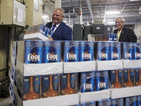 Ontario Premier Doug Ford, left, and Ontario Finance Minister Vic Fedeli, stack cases of beer during a photo opportunity at a brewery in Etobicoke, Ont. on Monday, Aug. 27, 2018. Buck a beer went into effect in Ontario on Monday, but only a handful of brewers have embraced the new, lower minimum price.
