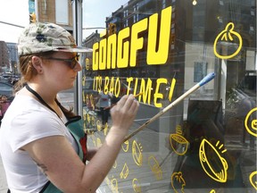 Ottawa artist Pascale Arpin hand paints a storefront sign on Bank Street on Thursday.  Tony Caldwell/Postmedia