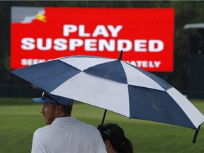 Patrons stand under an umbrella as play was suspended for the rest of the day during the second round of the PGA Championship at Bellerive Country Club in St. Louis on Friday. Play was suspended because of heavy rain.