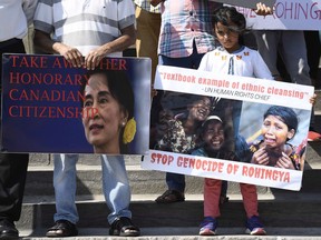 People hold signs against Myanmar leader Aung San Suu Kyi and the killing of the Rohingya people during a rally for Rohingya Genocide Remembrance Day on Parliament Hill on Saturday, Aug. 25, 2018.