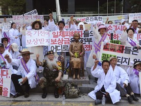 South Korean family members of the World War II victims shout an anti-Japan slogan during a rally in front of the Japanese Embassy to mark the South Korean Liberation Day from Japanese colonial rule in 1945, in Seoul, South Korea, Wednesday, Aug. 15, 2018. The signs read " Apology and Compensation from Japanese Government."