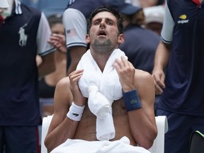 Novak Djokovic takes a break amid scorching heat during his first-round match against Marton Fucsovics at the U.S. Open on Aug. 28.