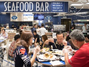 People eat at a seafood bar at T&T Supermarket's newest location, in Richmond, B.C., on Tuesday August 21, 2018. Shoppers can purchase fresh seafood in the store and have it steamed or baked to be eaten on site. Grocery stores increasingly blur the line between supermarkets and restaurants with large chains adding take-out meals to their shelves, hot food counters where chefs make dishes to order and even full-service restaurants. Dubbed grocerants, these combination spaces serve a time-strapped population that values convenience.