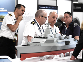 People surround a model of a BAE Systems Type 26 Global Combat Ship at the Canadian Association of Defence and Security Industries CANSEC trade show in Ottawa in May 2018.