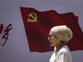 URUMQI, CHINA - JUNE 27:  Uighurs pass the Communist Party of China flag on the wall on June 27, 2017 in Urumqi, China.