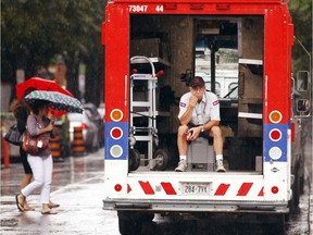 A Canada Post worker takes shelter from the rain.