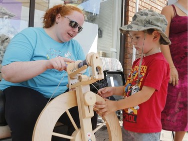 Robin Cole of Wabi-Sabi shows Riley, 4, how to spin wool into yarn at the Taste of Wellington West. Patrick Doyle/Postmedia