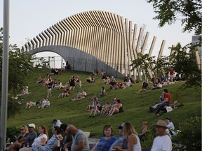 People watch from the vantage point of a grass-covered slope as Whitehorse performs on the last evening of CityFolk at Lansdowne Park on Sunday.