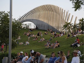 People watch from the vantage point of a grass-covered slope as Whitehorse performs on the last evening of CityFolk at Lansdowne Park in Ottawa on Sept. 16, 2018.