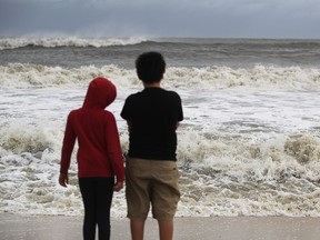 DAUPHIN ISLAND, AL - SEPTEMBER 04: Isabella Roberson (L) and Stanely Roberson look out at the waves crashing along the coastline from Tropical Storm Gordon on September 4, 2018 in Dauphin Island, Alabama.   Gordon heads for the northern Gulf Coast area as a strong tropical storm and could possibly strengthen into a Category 1 hurricane.
