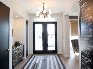 in the foyer, a "carpet" of black-and-white tile sets the tone. In one of several examples in the home of using simple and inexpensive tiles in unexpected ways, designer Tanya Collins created a grid pattern and inset the tile into the hardwood for an "amazing tile feature." Julie Oliver/Postmedia