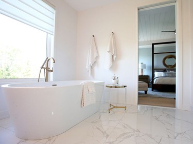 A Maxx Louie soaker tub beckons in the master ensuite, which is bathed in shades of white and gold for a calm and luxurious feel. It has the look of marble, but is done in a more affordable ceramic tile. Julie Oliver/Postmedia