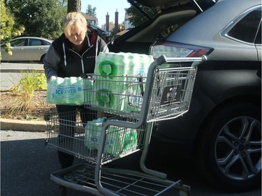 Raymond unloads water from her car into a residence housing seniors Monday morning.