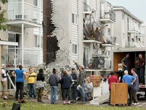 A group of neighbours helps one women move out her belongings from one of the damaged low rises in Mont-Bleu.