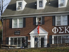 In this Friday, Nov. 17, 2017 photo, Brothers of the Phi Sigma Kappa Epsilon fraternity house take down a flag at Ohio State University in Columbus, Ohio. Ohio State has joined a growing list of schools hitting pause on Greek life as they grapple with how to prevent hazing, alcohol misuse and other misconduct.