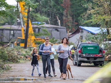 Parkland Court resident Heather Young takes her kids, Ella, 14, Zaiah, 12, and Rylan, 8, for a walk around their home as Arlington Woods continues to be a beehive of activity with arborists, hydro workers and city crews continuing to repair the damage from Friday's tornado.
