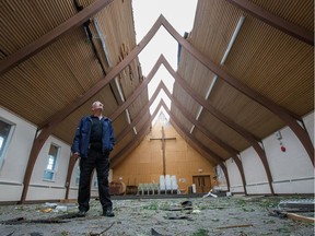 Barrie Pritchard, a volunteer at Arlington Woods Free Methodist Church, surveys the damage in the main hall, which had a good portion of the roof blown off by Friday's tornado. Wayne Cuddington/Postmedia