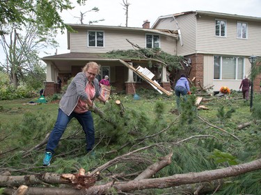 Volunteers, including Peggis Slavin, came to help clear brush, branches and logs from Tracey Graham's home on Parkland Cres on Sunday morning as residents in Ottawa's Arlington Woods neighbourhood  deal with the aftermath of the twister.