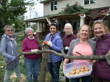 Tracey Graham (R) with her new best friends, volunteers that came to help clear brush, branches and logs from her home on Parkland Cres on Sunday morning as residents in Ottawa's Arlington Woods neighbourhood deal with the aftermath of the twister.