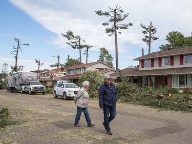 Pedestrians stroll along Riverbrook Rd on Sunday morning as residents in Ottawa's Arlington Woods neighbourhood deal with the aftermath of the twister.