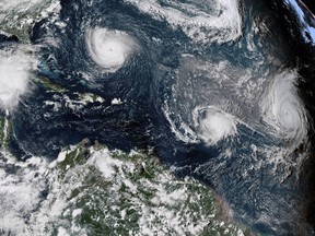 This enhanced satellite image made available by NOAA shows Tropical Storm Florence, upper left, in the Atlantic Ocean on Tuesday, Sept. 11, 2018 at 3:30 p.m. EDT. At center is Tropical Storm Isaac and at right is Hurricane Helene.