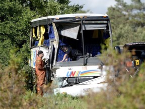 OPP officers work at the site of a crash involving a tour bus on Highway 401 West, near Prescott, Ont. June 4. Three Chinese tourists died and about two dozen people were injured.